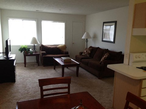 A living room with a brown couch and a wooden table.