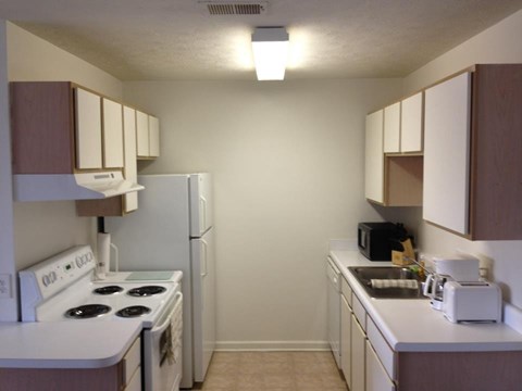 A small kitchen with white appliances and brown cabinets.