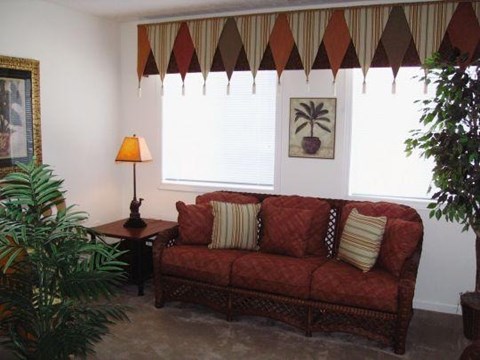 A living room with a red couch and a lamp.