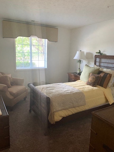 A bedroom with a bed, chair, and lamp.