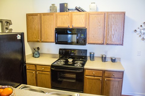 A kitchen with wooden cabinets and black appliances.
