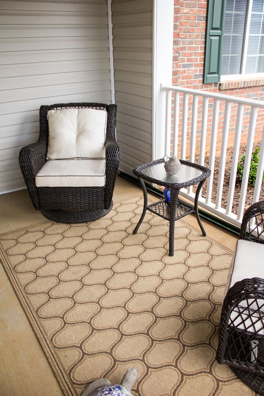 a porch with a wicker chair and a small table on it