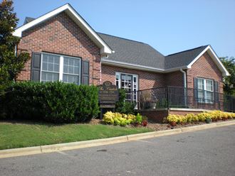 the front of a brick house with a black wrought iron fence in front of it