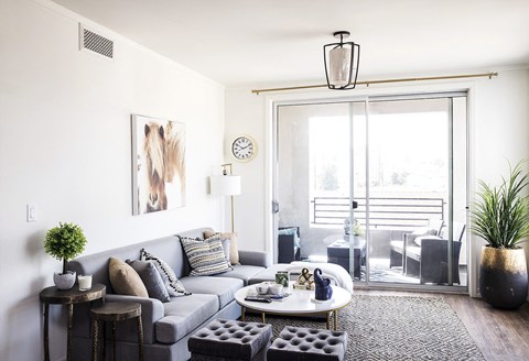 A living room with a grey couch, a coffee table, and a painting of a horse on the wall.