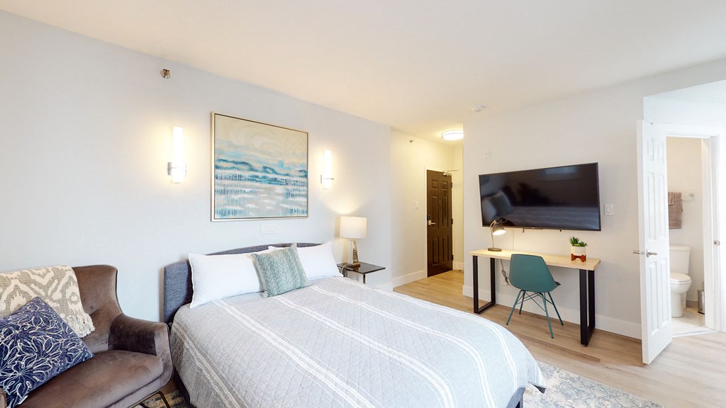 a bedroom with a bed and a desk with a television