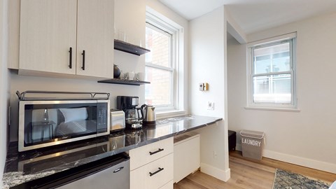 a kitchen with white cabinets and a black counter top and a microwave