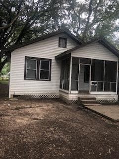 A small white house with a porch and a covered entry way.