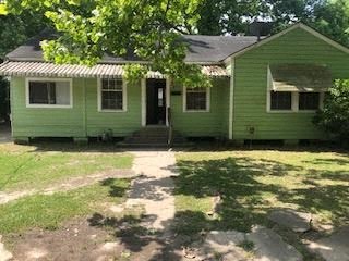 a green house with a tree in front of it