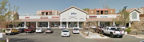 A parking lot in front of a store with cars parked.