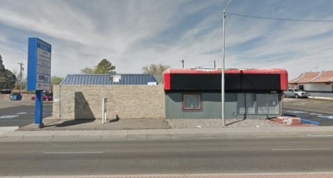A bus stop with a red awning is located on the side of a road.