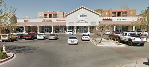 A parking lot in front of a store with cars parked.