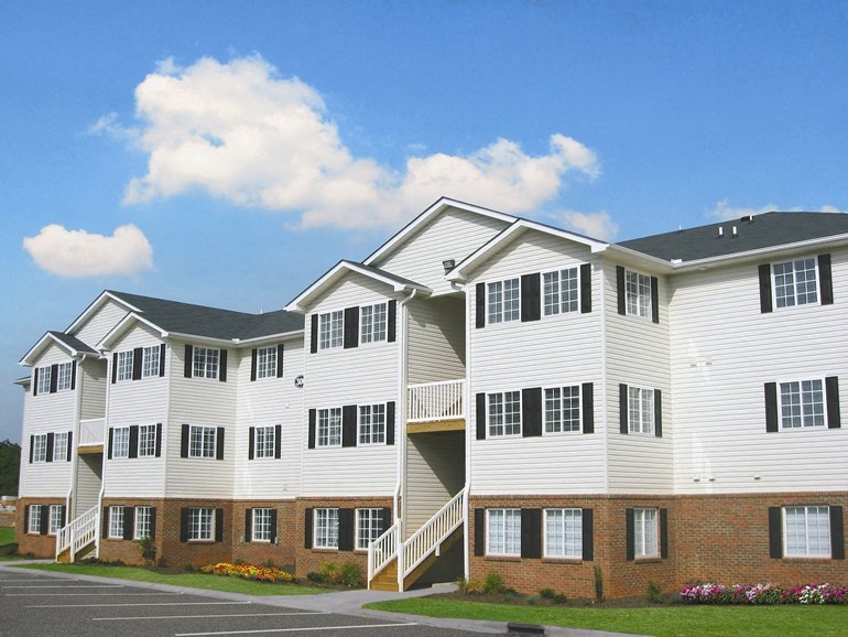 a building with white siding and a street in front of it