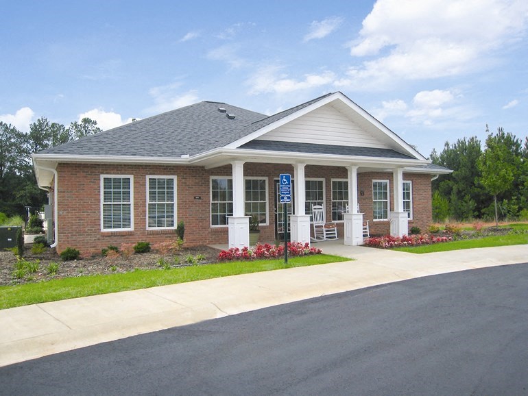 the front of a brick building with a porch and a driveway