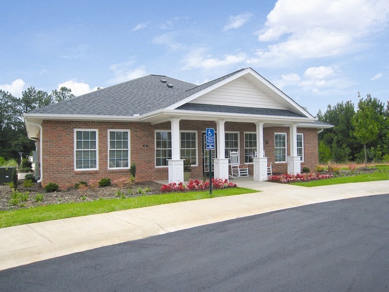 the front of a brick building with a porch and a driveway