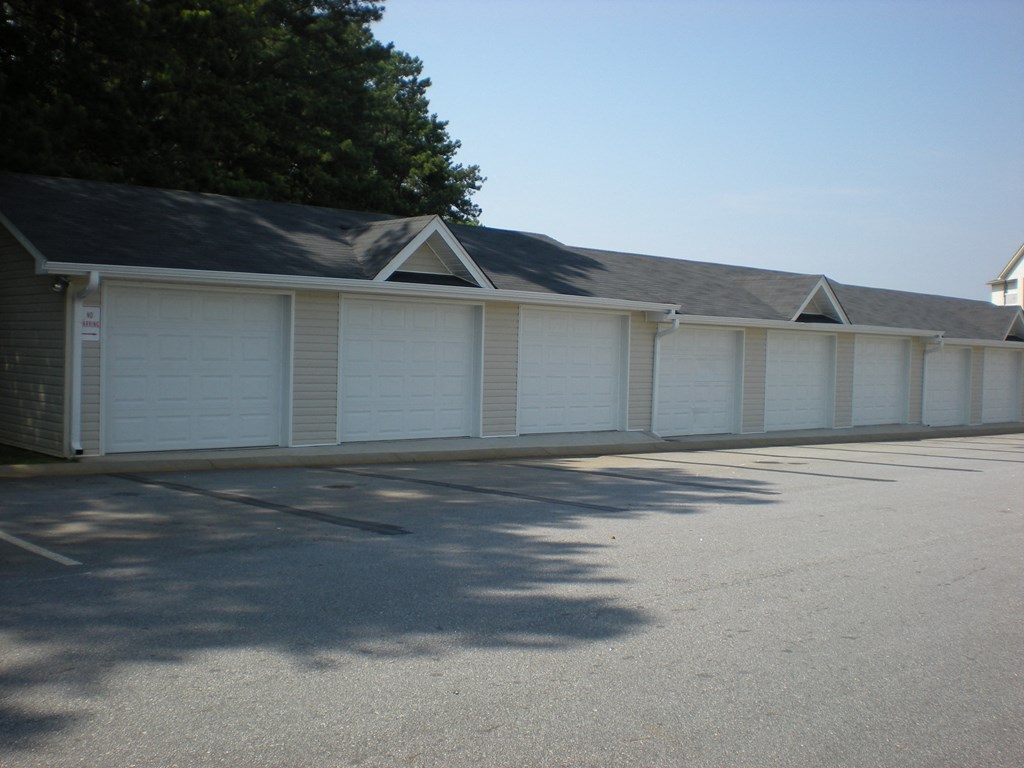 a row of white garage doors in a parking lot