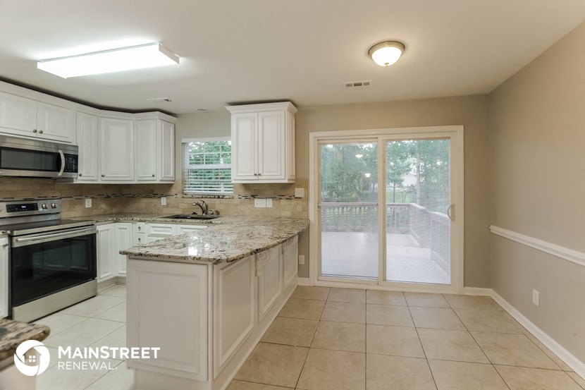 a kitchen with white cabinets and granite counter tops and a backdoor to a patio