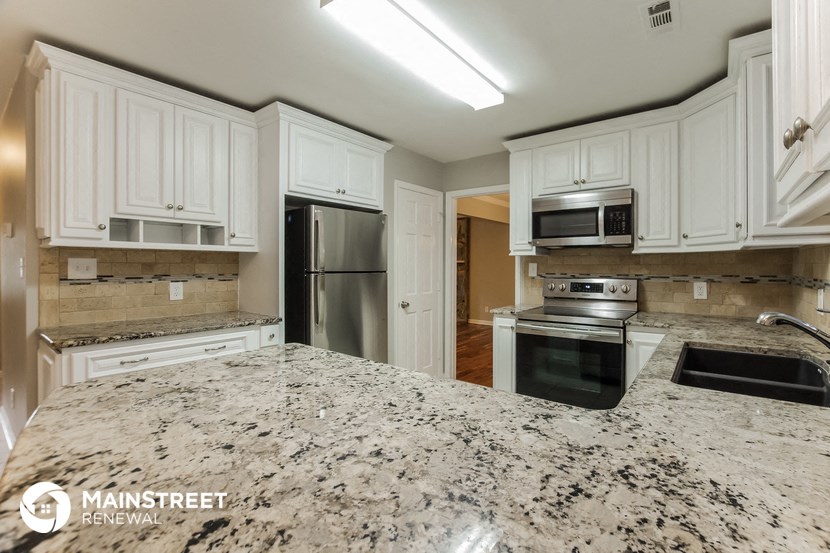 a kitchen with granite counter tops and white cabinets and stainless steel appliances