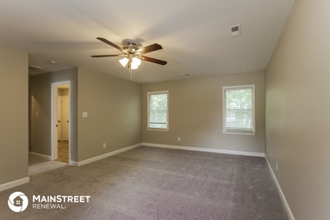 the spacious living room with carpet and ceiling fan