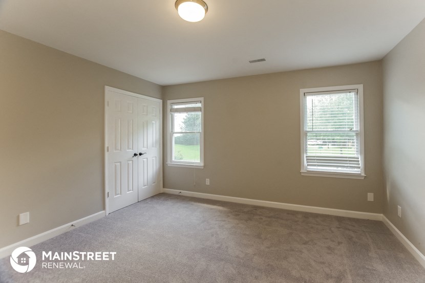 a bedroom with a carpeted floor and a white door and window