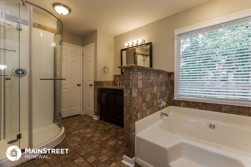 the master bathroom has a large tub and a walk in shower