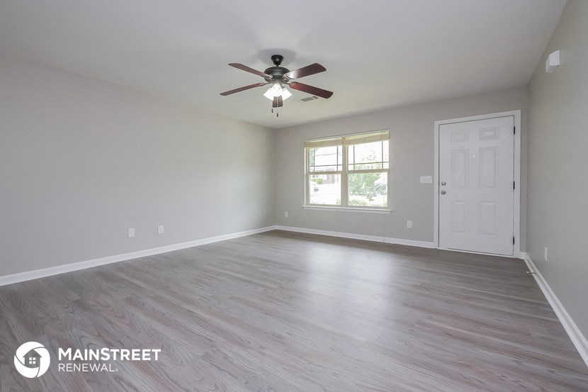 the living room of an empty house with a ceiling fan