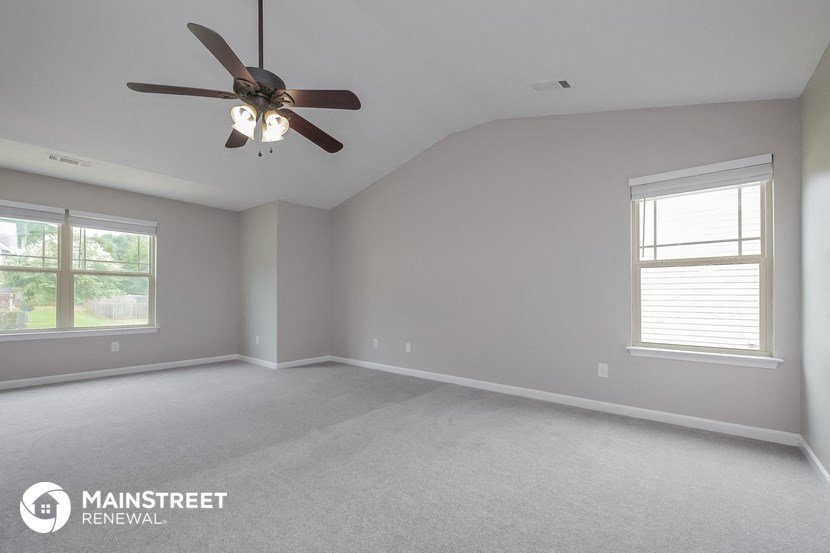 the living room of a home with a ceiling fan and two windows