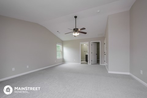 the spacious living room with ceiling fan and white carpet