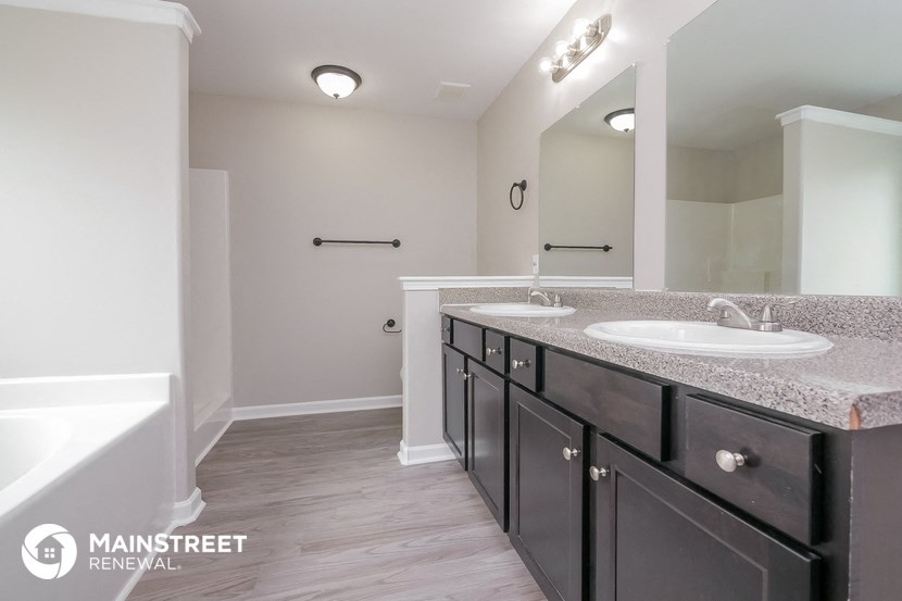 a bathroom with two sinks and a tub and a large mirror