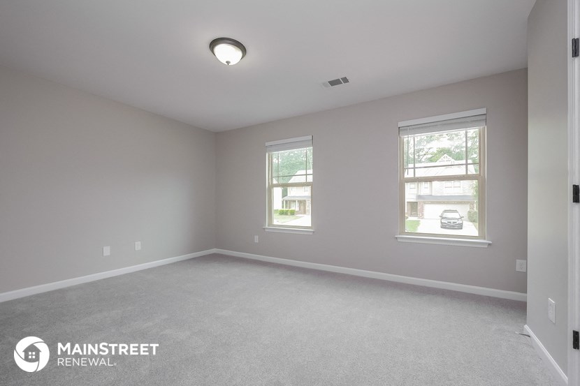 the master bedroom with carpeted flooring and two windows