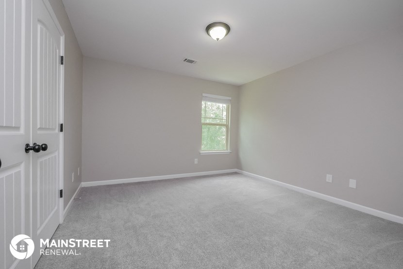 the spacious living room with white carpet and a white door