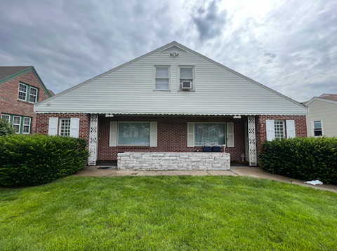 A house with a red brick wall and a white porch.