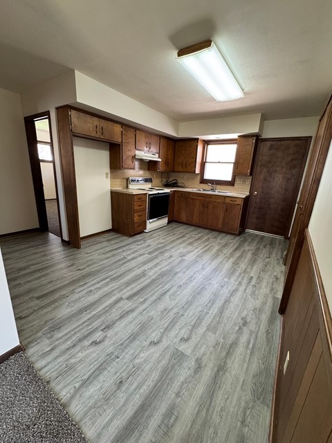 A kitchen with wooden cabinets and a grey floor.