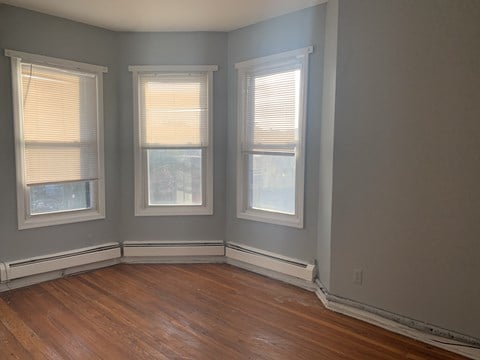 three windows in a room with wooden floors and gray walls