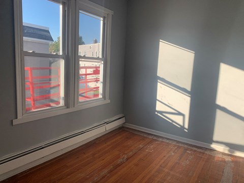an empty room with three windows and a wooden floor
