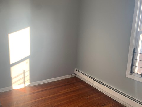 the corner of a room with wooden floors and white walls