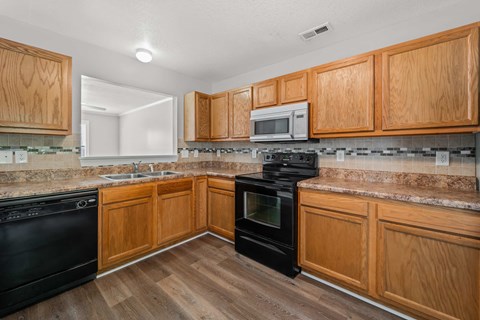 A kitchen with wooden cabinets and black appliances.