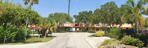 a building with palm trees and a road in front of it