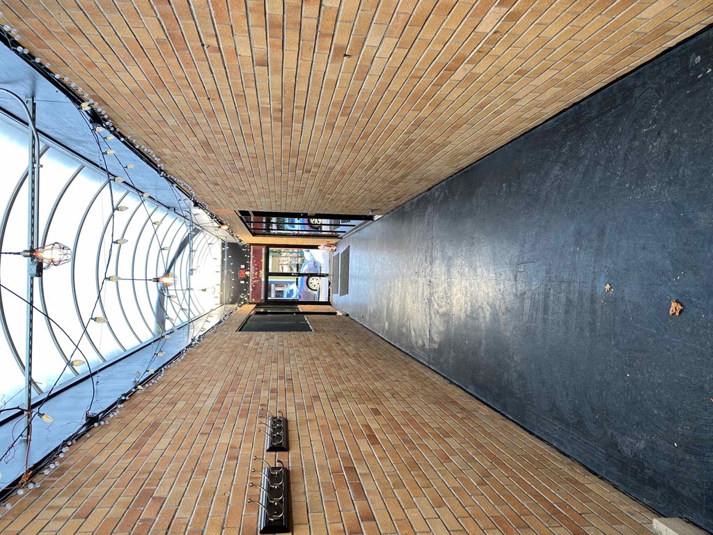 a long corridor with wooden floors and a black wall on the side