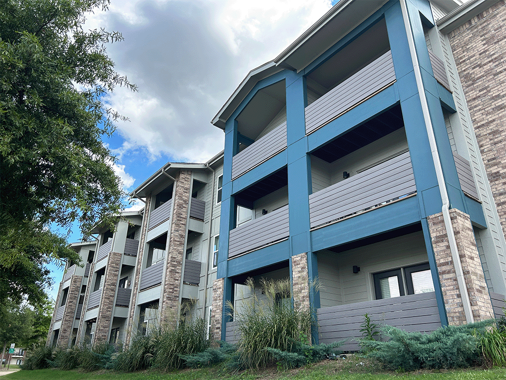 an apartment building with blue balconies on a cloudy day