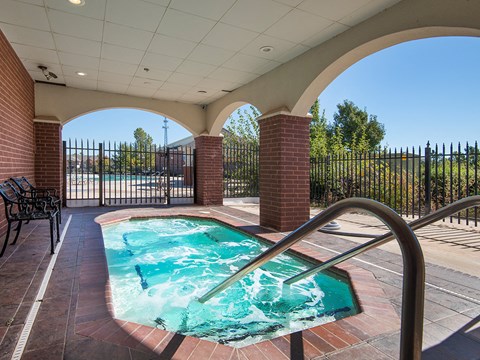 the resort style hot tub in the pool area of a building with a black fence