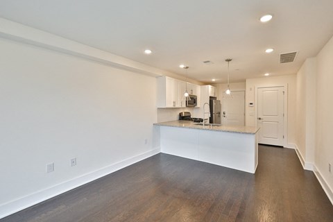 an empty living room and kitchen with white walls and wood floors