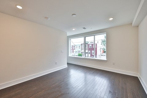 an empty living room with wood floors and a large window