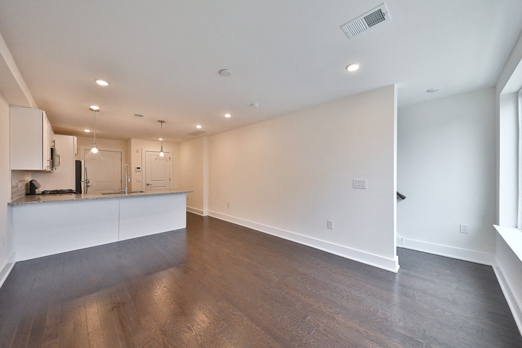 an empty living room and kitchen with white walls and wood flooring