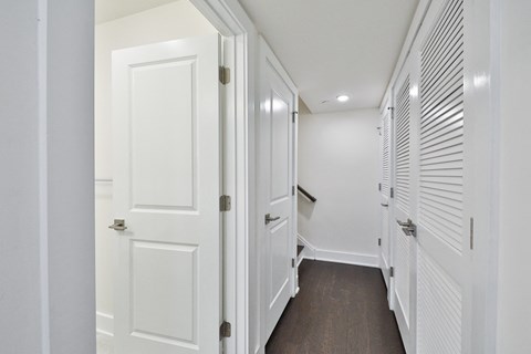 a hallway with white closets and doors and a wood floor