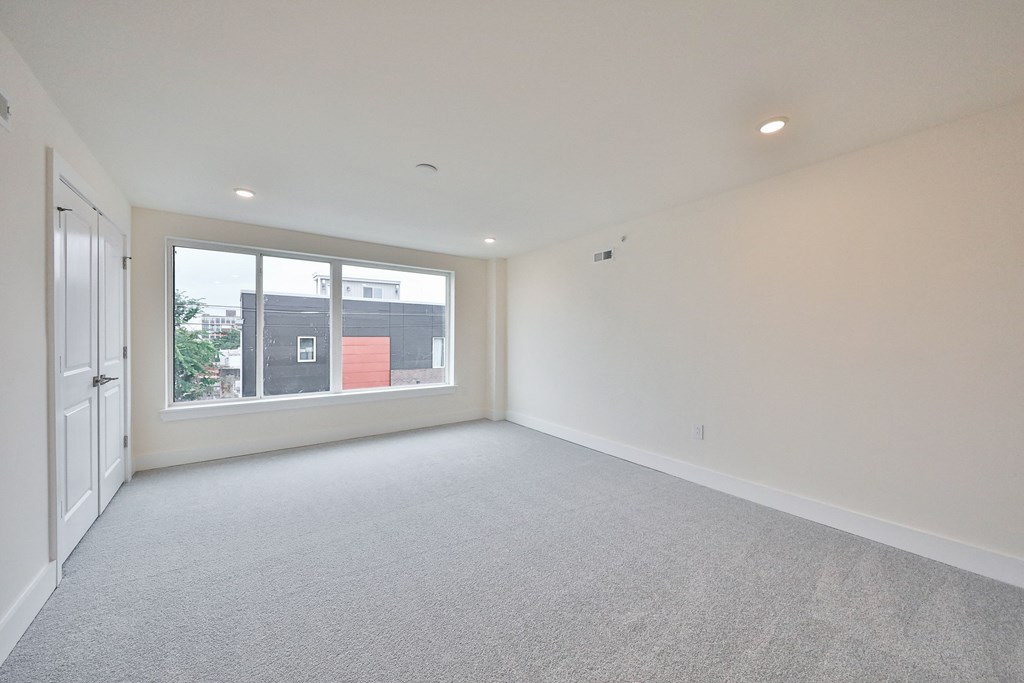 an empty living room with a large window and white walls
