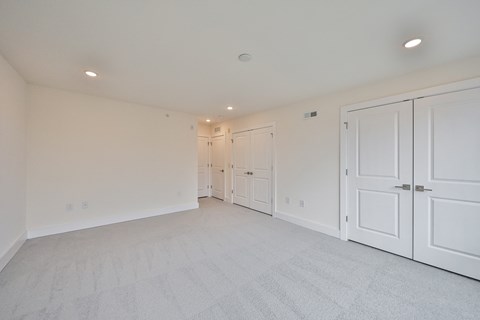 a bedroom with white closets and white carpeting and white doors