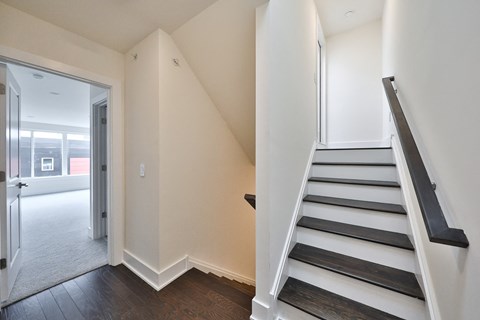 an empty hallway with a staircase and a door to a living room