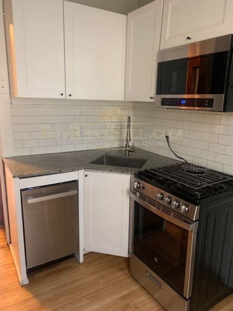 A kitchen with white cabinets and a black stove top oven.