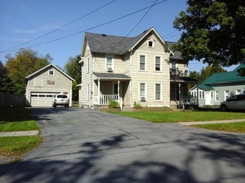A large house with a garage is situated on a street.