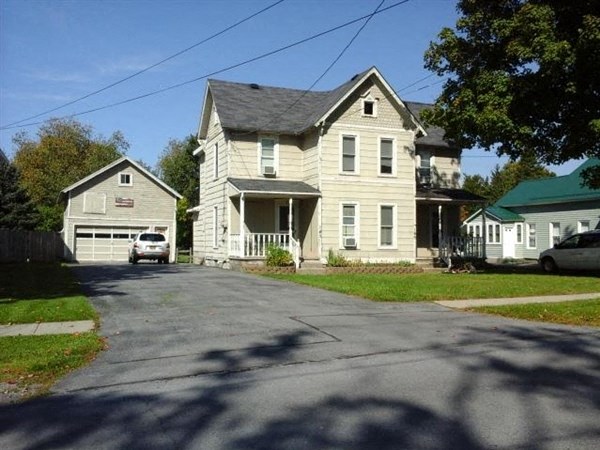 A large house with a garage is situated on a street.